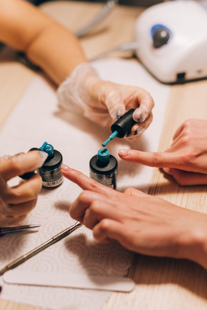 Close-up of a manicurist applying gel polish to a clients nails with precision.
