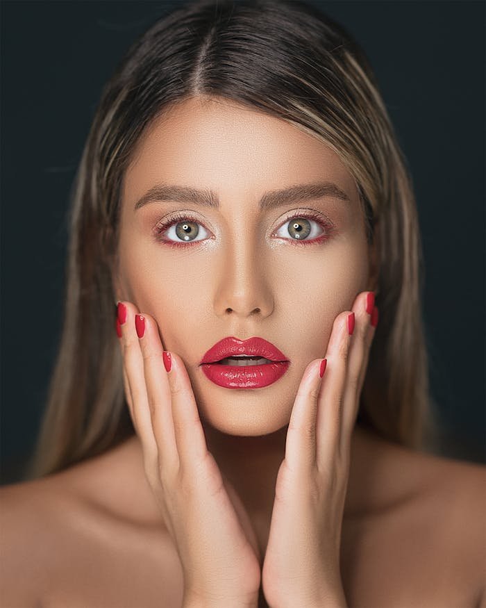 Close-up portrait of a woman showcasing red lips and nails, emphasizing beauty and elegance.